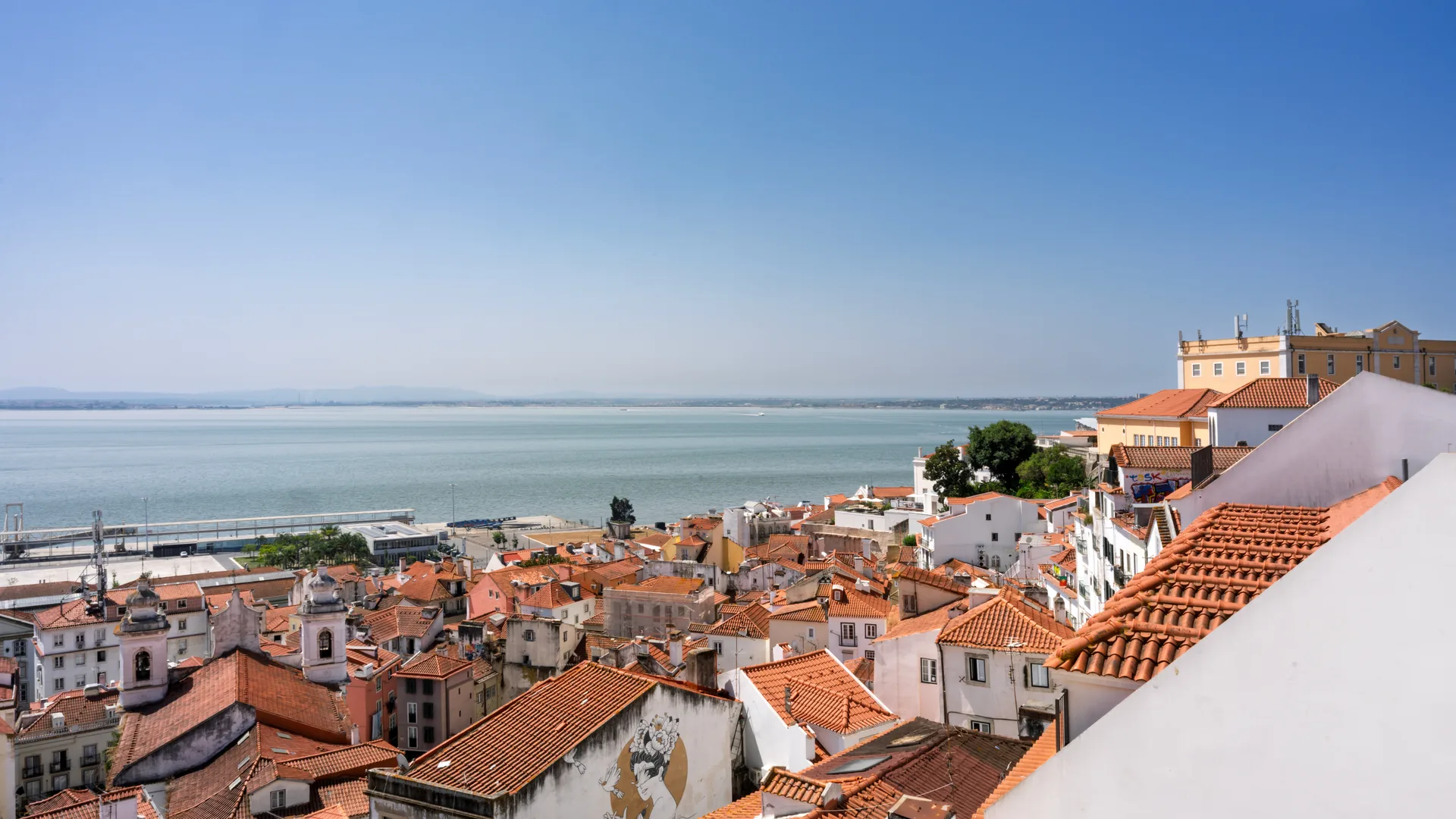 Toits en terre cuite de l'Alfama et vue sur le Tage à Lisbonne