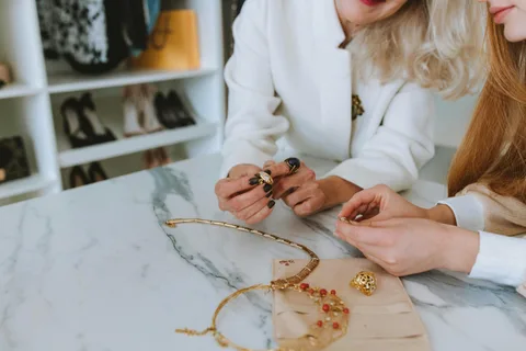 Sales advisor presenting a gold necklace to a customer on a marble table